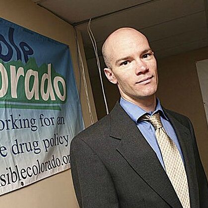 A photo of Brian Vicente standing in front of Sensible Colorado banner.
