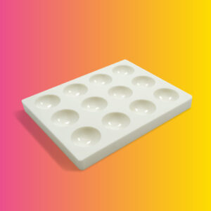 A white palette plate with 12 round divvets in it on a gradient background.