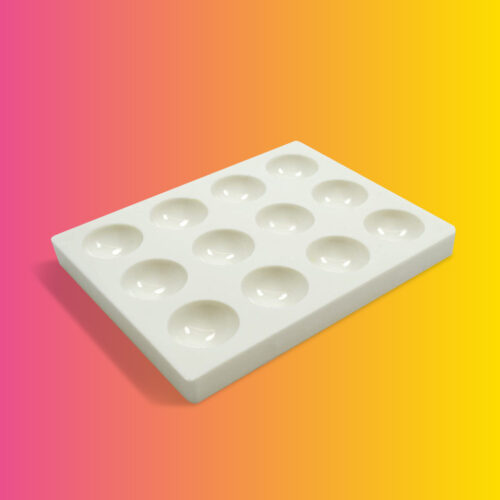 A white palette plate with 12 round divvets in it on a gradient background.