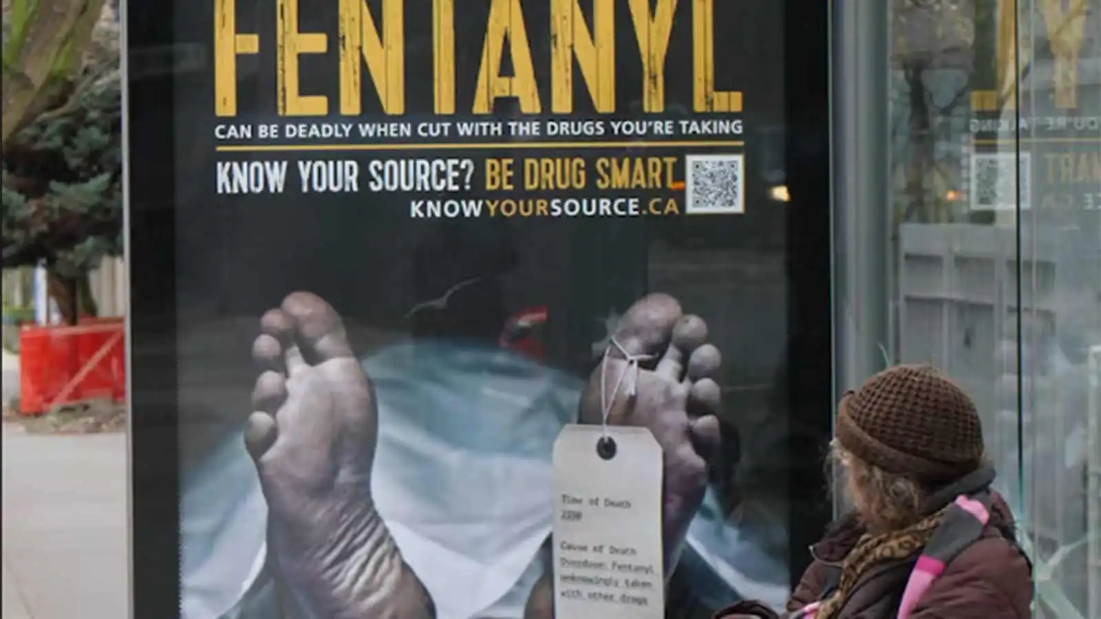 A photo of a fentanyl cautionary board in a public place, with someone standing in front of it.