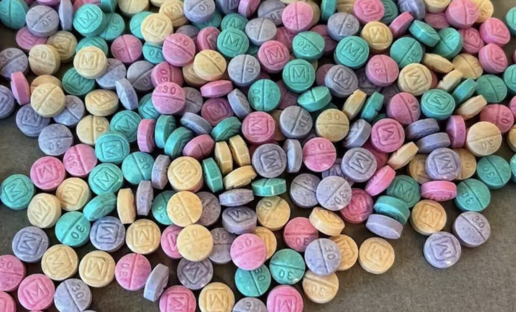 An aerial shot of multicolored counterfeit oxycodone 30 mg pills, so-called 