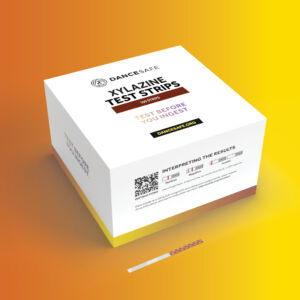 White and yellow box labeled “DanceSafe Xylazine Test Strips – 100 Strips” displayed against an orange-yellow gradient. The box features the DanceSafe logo, a QR code for instructions, result interpretation examples, and the phrase “Test Before You Ingest.”
